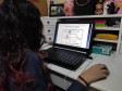 A estudante do curso de Fotografia do CJAP, Laura Pacheco, estuda o conteúdo enviado em seu computador.