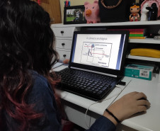 A estudante do curso de Fotografia do CJAP, Laura Pacheco, estuda o conteúdo enviado em seu computador.