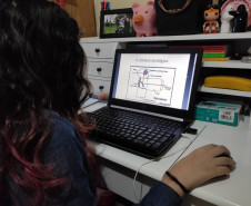 A estudante do curso de Fotografia do CJAP, Laura Pacheco, estuda o conteúdo enviado em seu computador.