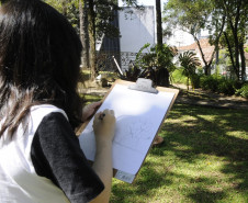 Aluna do CJAP desenha em atividade ao ar livre no Museu Paranaense.