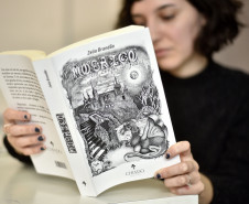 Luiza Urban e o livro de contos "Mosaicos" com ilustrações de sua autoria.