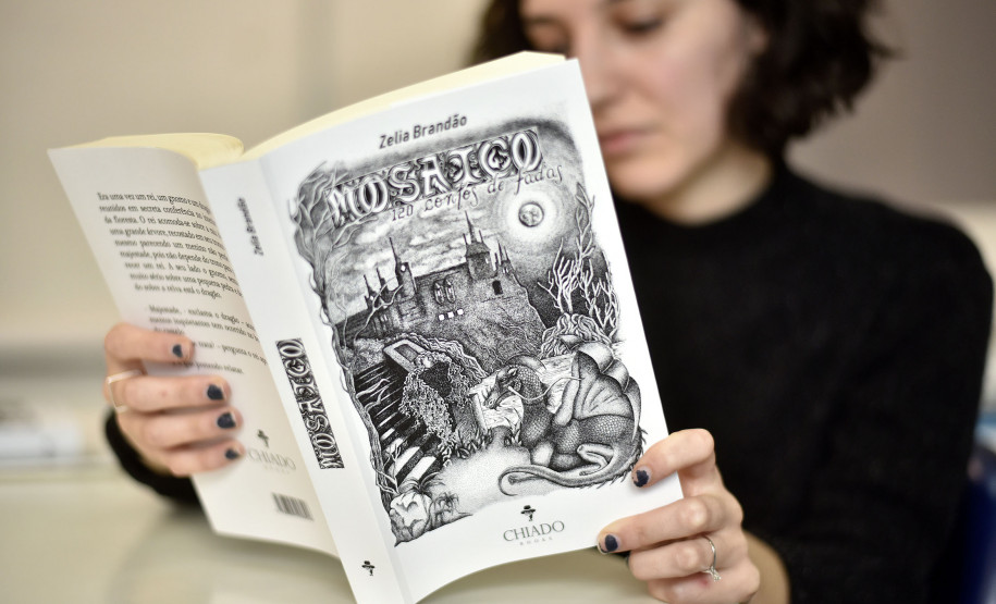 Luiza Urban e o livro de contos "Mosaicos" com ilustrações de sua autoria.